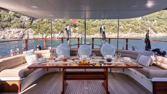 Bodrumda gulet kiralama seçeneği Kaftan arka güvertede geniş oturma grubu yemek masası ve deniz manzarası ile konfor sun