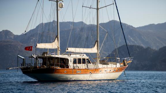 Bodrumda gulet kiralama seçeneği Kaftan denizde arka açıdan görünüm geniş güverte ve dağ manzarası ile dikkat çekiyor.