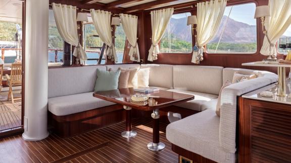 Bodrumda gulet kiralama seçeneği Kaftan salon içinde köşe oturma grubu masa düzeni ve deniz manzarası ile rahat ortam su