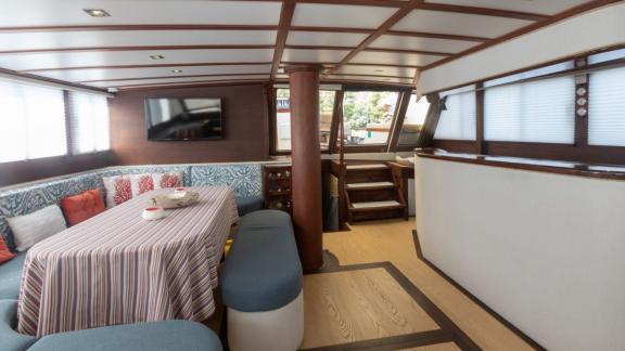 Komfortabler Wohnbereich mit Esstisch und Fernseher im Inneren der Yacht Kanarya.