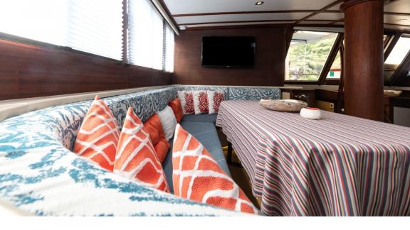 Comfortable seating area with colorful cushions and dining table inside Yacht Kanarya.