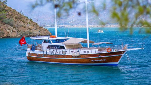 The Gulet Kasapoglu 6 is anchored in a scenic bay near Fethiye, surrounded by green hills.