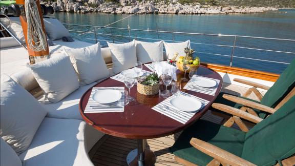 На Родосе аренда гулета Lady Freya носовая палуба со столом мягкими сиденьями и видом на море.