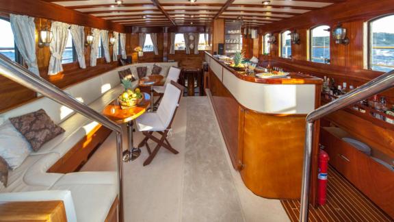 Elegant interior of a gulet with bar, sofas and large windows offering sea views.