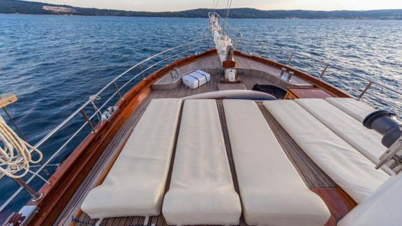 A gulet on Croatian waters with sunbathing areas on the foredeck, surrounded by calm sea and coastal scenery.