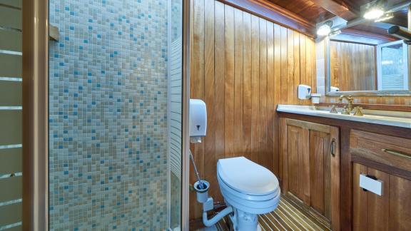 Bathroom on a gulet with wooden walls, mosaic tiled shower and washbasin.