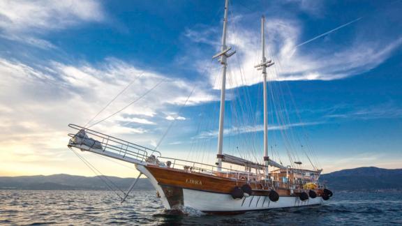 A charter gulet with 6 cabins from Croatia, sailing on the sea with mountains in the background.