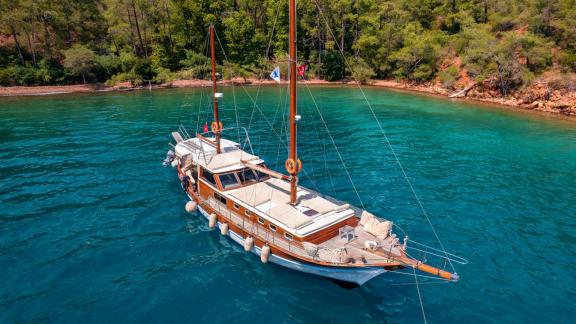 The Gulet Lina 2 anchored in a picturesque bay with turquoise water, surrounded by green vegetation.