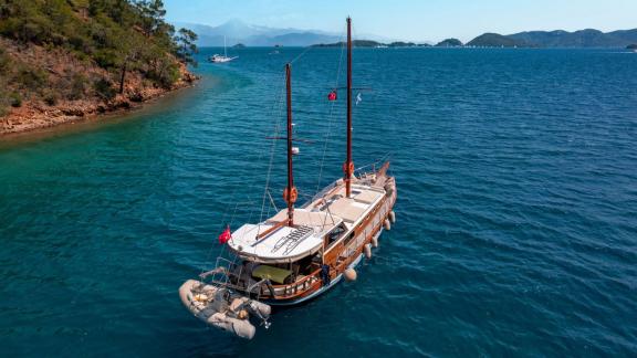 The Gulet Lina 2 sailing in a wide bay with turquoise water, surrounded by wooded hills.