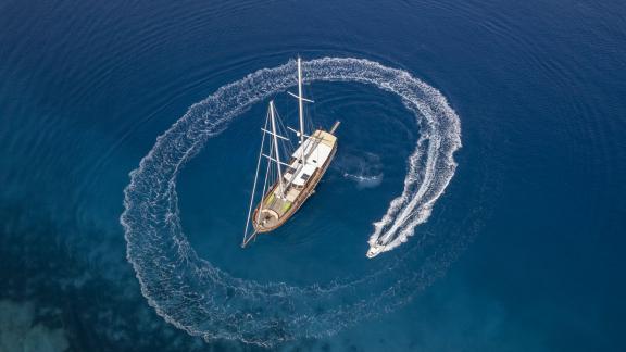 Die Gulet Lorient wird von einem kleinen Beiboot umkreist, während sie in den tiefblauen Gewässern von Bodrum liegt.