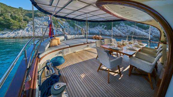 Dining area on the gulet Lotus in Croatia, with elegant furniture and a laid table.