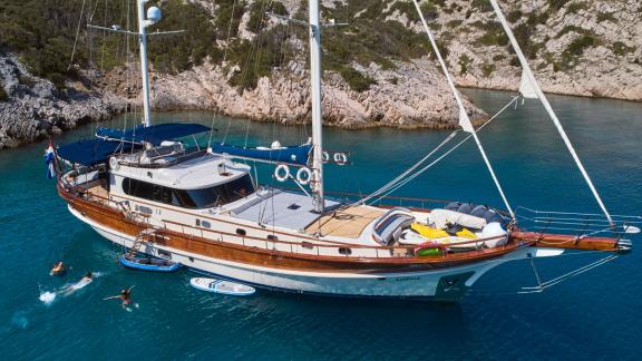 The gulet Lotus is anchored in a clear bay in Croatia, while guests enjoy the sunny weather while swimming and doing wat