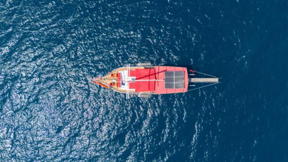 Luftaufnahme der Gulet Lycian Sirius mit rotem Sonnenschutz, die im blauen Meer vor Fethiye segelt.