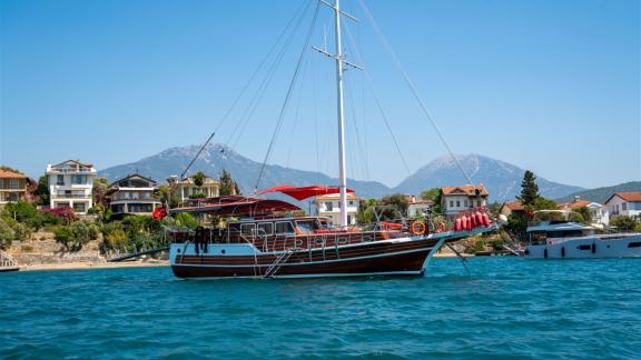 Die Gulet Lycian Sirius liegt vor Anker in Fethiye, umgeben von Küstenhäusern und mit Bergen im Hintergrund.