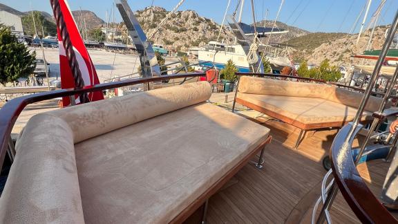 Auf der Mietgulet Mare Magico in Marmaris sind Hecksofas, Holzdeck und Blick auf die Marina zu sehen.