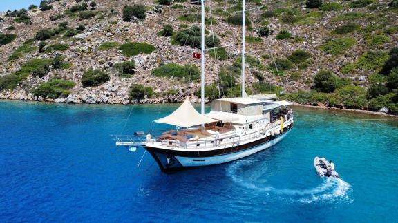 Die Charter Gulet Mare Magico liegt vor Marmaris in einer türkisblauen Bucht vor Anker, mit Sonnensegel und Beiboot.