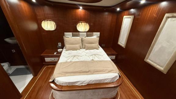 In der Mietgulet Mare Magico sind Doppelbett, runde Fenster und glänzendes Holzinterieur zu sehen.
