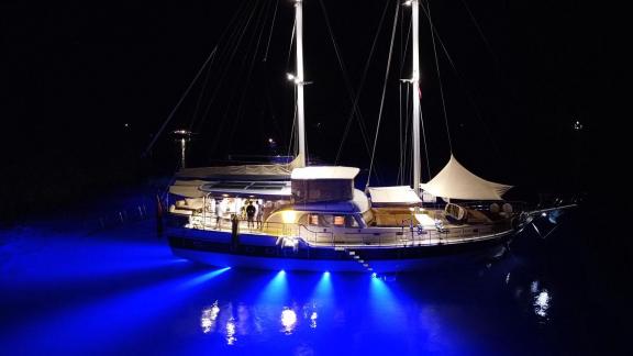 Die Mietgulet Mare Magico zeigt sich nachts in Marmaris mit hellen Masten, blauem Unterwasserlicht und Spiegelung.