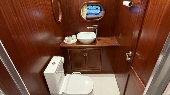 In der Mare Magico Mietgulet in Marmaris sind Waschbecken, WC, ovales Fenster und Holzschrank zu sehen.