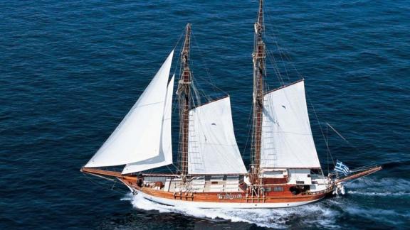 The gulet Matina sails majestically across the open sea in Greece with a Greek flag on the bow.