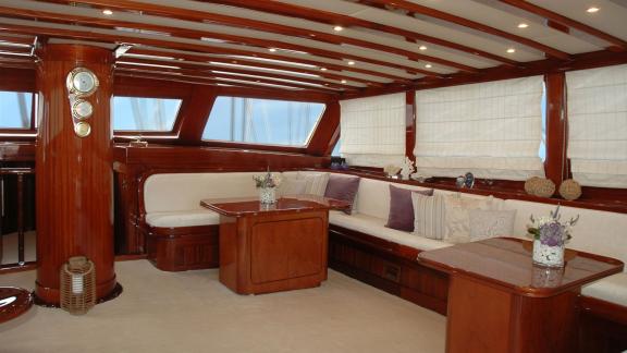 An elegant lounge on the Gulet Matina with wooden furnishings, cosy sofas and large windows