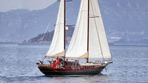 Gulet Mikado mit vollen Segeln auf dem blauen Meer von Marmaris, umgeben von Bergen.