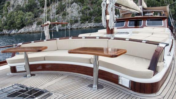 Elegant seating area on the deck of Gulet Mikado, overlooking clear waters and green shores.