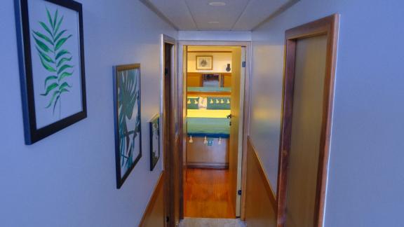 A narrow hallway leads to a welcoming cabin with warm wood decor and maritime accents.