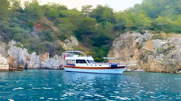 This 3-cabin gulet for 6 people is anchored in a quiet bay with turquoise waters and rocky cliffs.