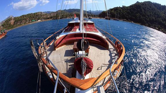 The foredeck of the Gulet Nirvana 2 with seating, forested hills, and coastline in the background.