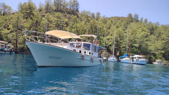 Die Gulet Nostalji vor Anker in Göcek, umgeben von anderen Booten und grünen Hügeln.