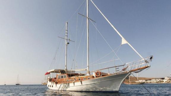 Die Gulet Okay 2 liegt ruhig vor Anker in den Gewässern von Bodrum, umgeben von einer malerischen Küstenlandschaft.