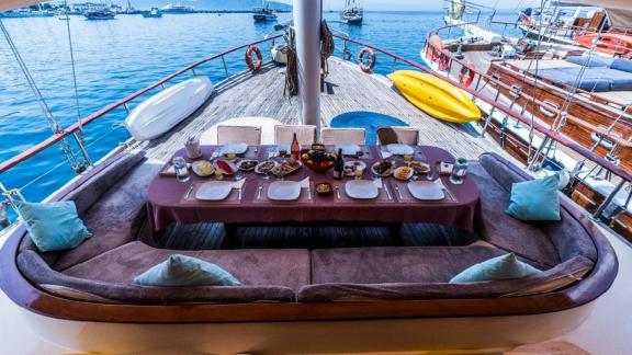 Cozy dining area on Gulet Optimist with a set table and a view of the sea and yachts.