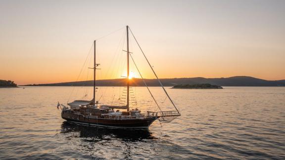 Die Gulet Pacha gleitet friedlich übers Wasser, während die Sonne malerisch hinter der kroatischen Küste untergeht.