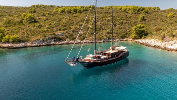 Die Gulet Pacha liegt vor Anker in einer stillen, unberührten Bucht mit türkisfarbenem Wasser und grüner Natur.