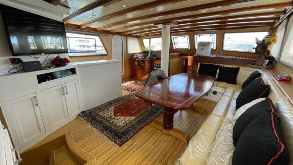 Pam gulet for 10 guests features a wooden indoor salon with a dining table and comfortable seating area.