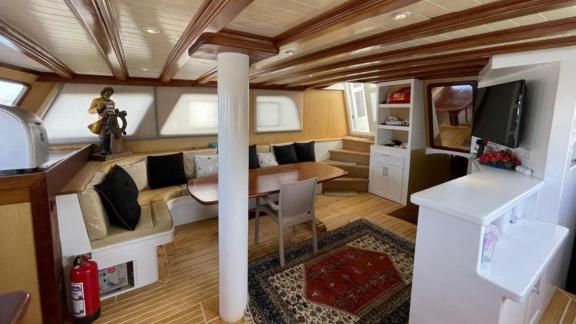 Pam gulet for 10 guests features a cozy indoor salon with wooden details and a dining table onboard.