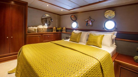 In der Perdue in Fethiye sind ein Doppelbett, runde Fenster und elegante Holzschränke zu sehen.
