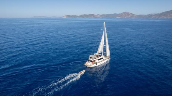 Die Perdue ist aus der Luft zu sehen. Sie segelt vor Fethiye mit gesetzten Segeln und Begleitboot.