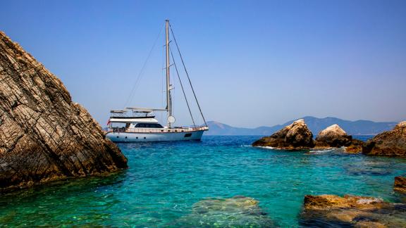 Die Perdue liegt in einer von Felsen umgebenen türkisfarbenen Bucht vor Fethiye vor Anker.