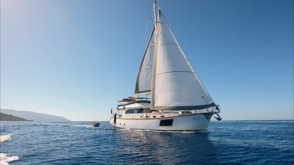 Die Perdue fährt vor Fethiye mit gesetzten Segeln. Der weiße Rumpf ist auf dem ruhigen Meer zu sehen.