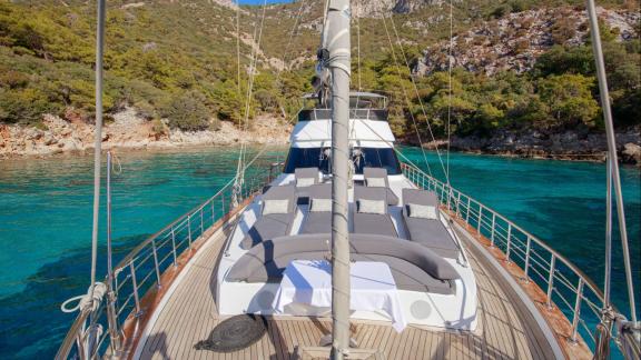 Zu sehen sind die Sonnenpolster und der Ruhebereich auf dem Vordeck der Perdue in einer türkisfarbenen Bucht bei Fethiye