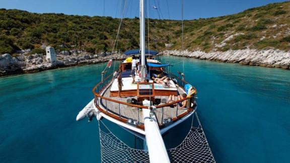 Die Gulet Perla liegt vor Anker in einer ruhigen, malerischen Bucht mit türkisfarbenem Wasser, umgeben von grüner Küsten