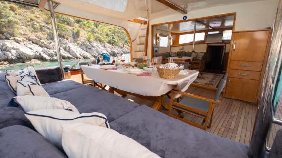Among Fethiye yacht rental options Queen Alin aft deck shows dining table and entrance to interior salon.