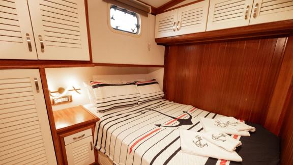 Among Fethiye yacht rental options Queen Alin cabin shows double bed and storage cabinets for comfortable stay.