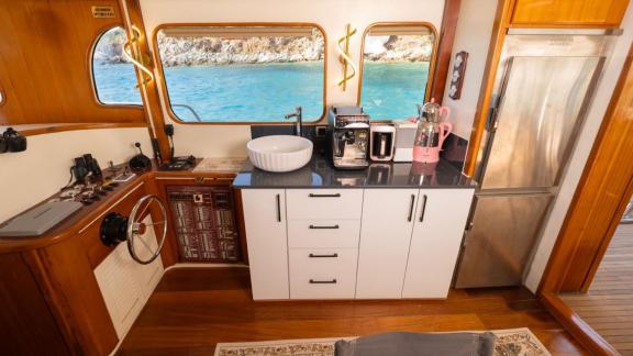 Among Fethiye yacht rental options Queen Alin interior shows kitchen area with sink appliances and control panel.