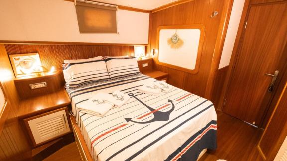 Among Fethiye yacht rental options Queen Alin cabin shows double bed and wooden interior design onboard.