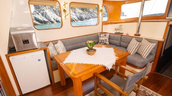 Among Fethiye yacht rental options Queen Alin interior shows seating area and dining table near windows.