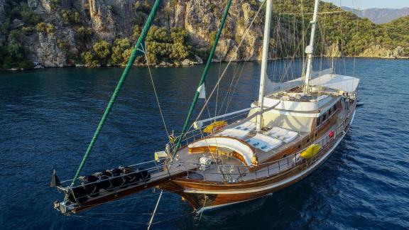 Nahaufnahme einer großen Segelyacht, die in einer ruhigen Bucht mit klarem, blauem Wasser vor Anker liegt.