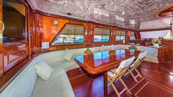 Sailing yacht with a large wooden dining table and a comfortable bench seat.